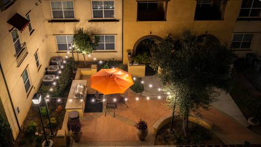 A patio with a table and chairs and an orange umbrella.