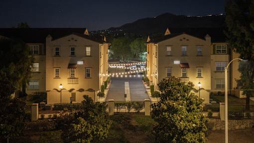 A residential area with two-story buildings and a street illuminated by streetlights.