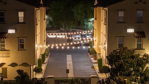 A street view of apartment buildings at night with lights on.