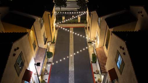 A narrow street with buildings on either side is illuminated by string lights.