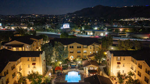 A pool in the middle of apartment buildings at night.