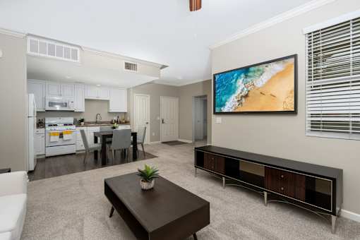 A modern living room with a kitchen in the background.