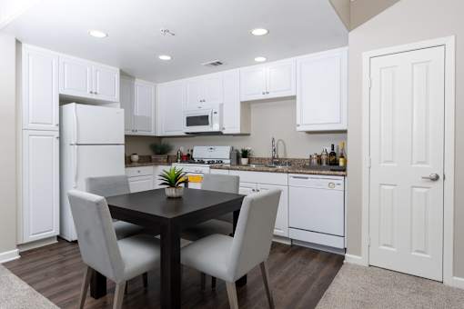 A kitchen with white cabinets and a black table.