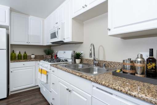 A kitchen with white cabinets and a granite countertop.