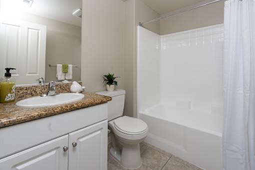 A white bathroom with a sink, toilet, and shower.