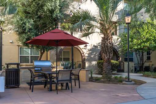 A patio with a table and chairs under a red umbrella.