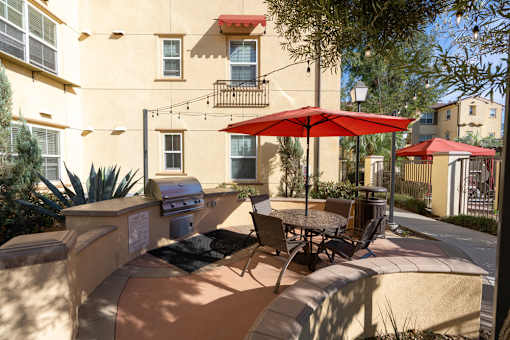 A patio with a table and chairs under a red umbrella.
