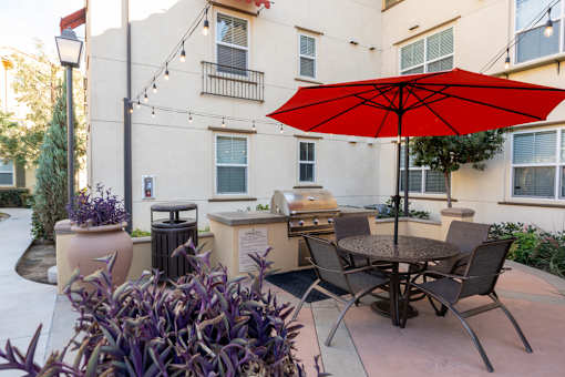 A patio with a table and chairs under a red umbrella.