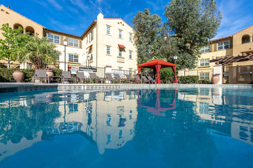 Red swing set is reflected in the water of a pool.