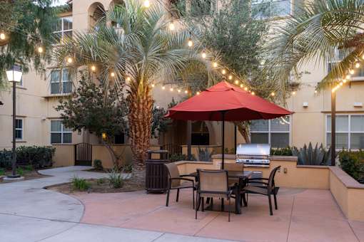 A red umbrella is on a patio table with chairs.