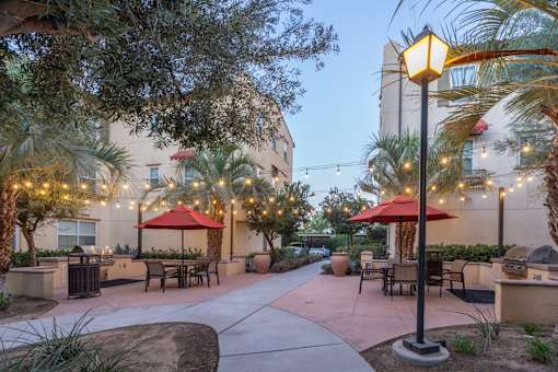 A patio area with tables and chairs is illuminated by string lights.