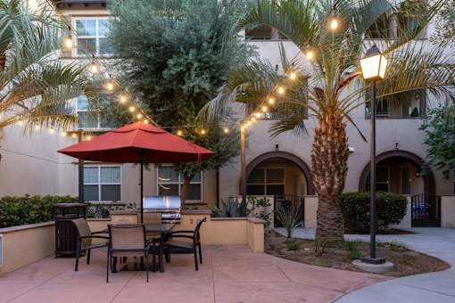 A patio with a table and chairs under a red umbrella.
