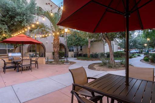 A patio with a table and chairs under a red umbrella.