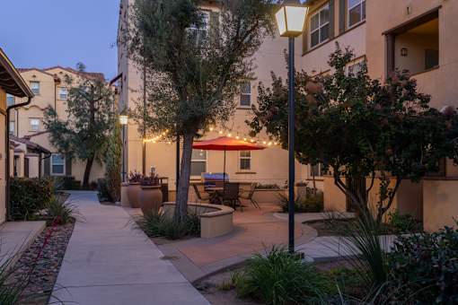 Patio with a table and chairs is surrounded by trees and plants.