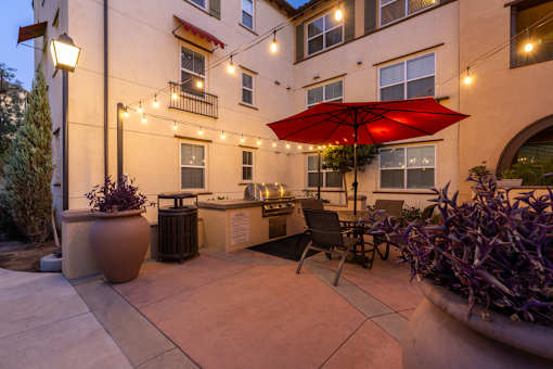 A red umbrella is on a patio with a table and chairs.