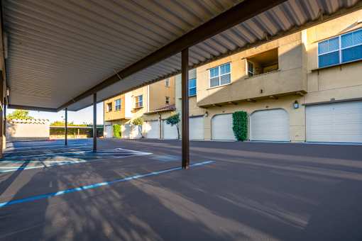 an empty parking lot in front of a building with white garage doors