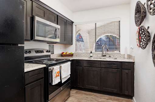 A kitchen with black cabinets and appliances.