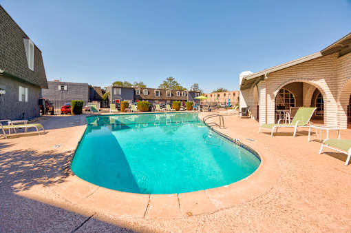 A small pool surrounded by a concrete floor and chairs.