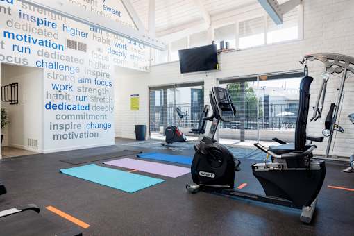 A gym with a wall of motivational words and exercise equipment.