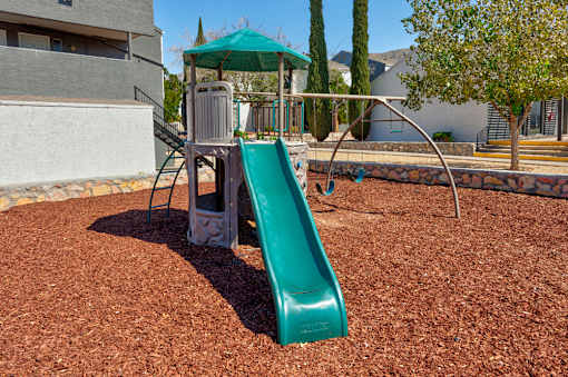 A green slide in a playground with a metal pole and a green canopy.