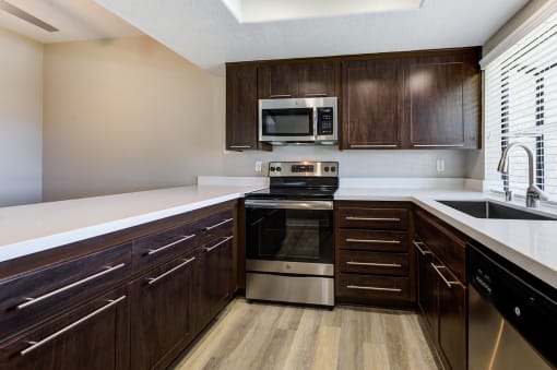 Apartments for Rent Laguna Niguel CA - Pointe Niguel - Kitchen with Wood-Style Floor, Brown Cabinets, White Quartz Countertops, and Stainless Steel Appliances at Pointe Niguel, Laguna Niguel, CA