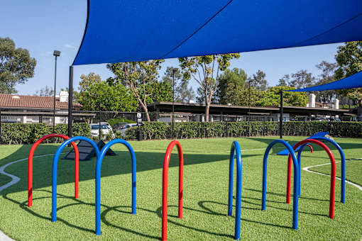A playground with a blue canopy and red and blue play structures.