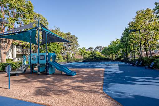 A playground with a blue slide and a green canopy.