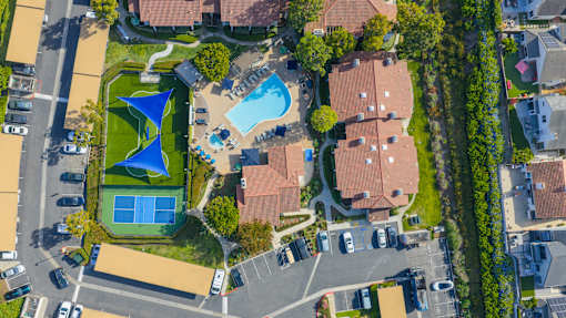 A bird's eye view of a residential area with a swimming pool and tennis court.