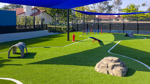 A playground with a blue canopy and a slide.