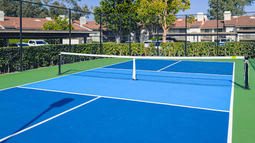 A blue tennis court with a white net in the middle.