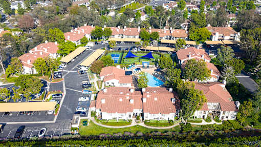 A bird's eye view of a residential area with houses, a swimming pool, and a parking lot.