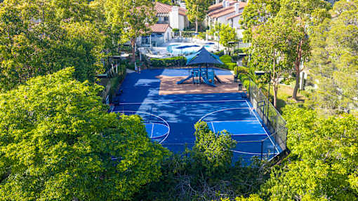A basketball court surrounded by trees and a gazebo.