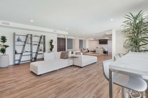 A white sofa set is placed in a room with wooden flooring at Wilshire Valencia Apartment, California