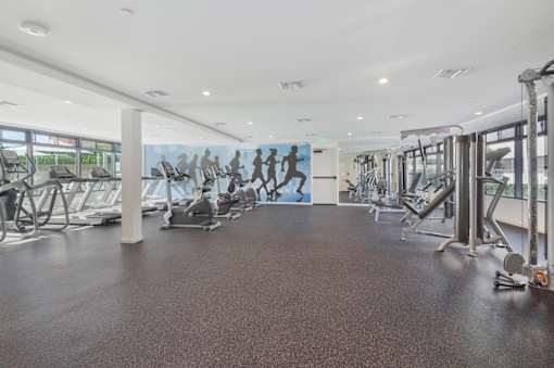 A gym with treadmills, elliptical machines, and other cardio equipment at Wilshire Valencia Apartment, Los Angeles, California