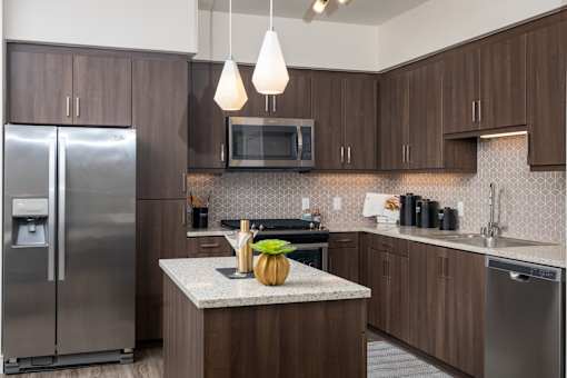 A kitchen with a refrigerator, microwave, and a counter with a pumpkin on it.