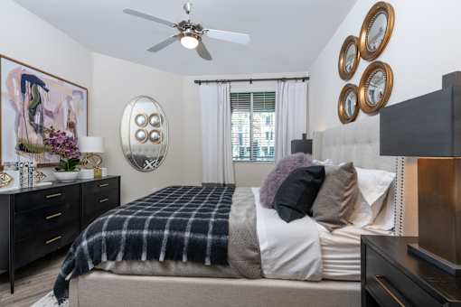 A bedroom with a bed, dresser, and a ceiling fan.