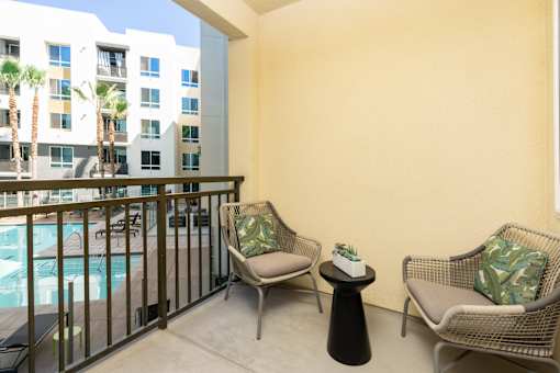 A balcony with two chairs and a table with a plant on it.