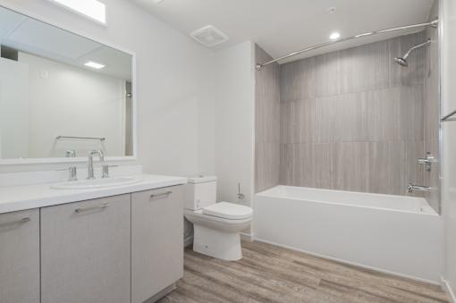 A white bathroom with a toilet, sink, and bathtub at Wilshire Valencia Apartment, Los Angeles