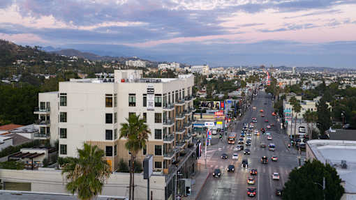 A busy street with cars and buildings under a cloudy sky. at Skyview Sunset, California