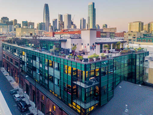 A modern building with green glass windows is in the foreground with a city skyline at Arc Light, California, 94107