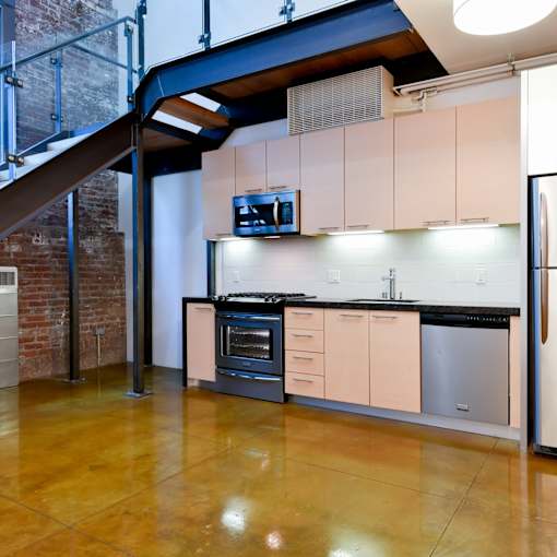 A kitchen with a stainless steel refrigerator and a black countertop.at Arc Light, San Francisco, CA 94107