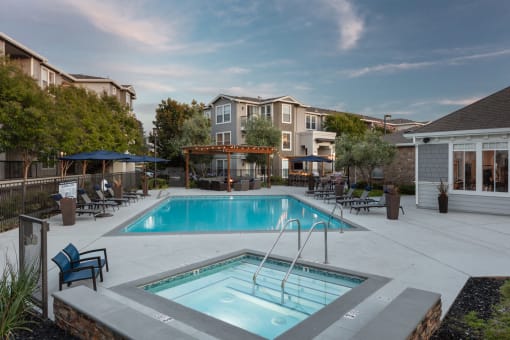 Salt Water Pool With Bubbling Spa, Lounge Chairs, Umbrellas, Outdoor Seating Area With Firepit Under A Pergola, And Outdoor Barbeque Area at Montrachet Apartments, California