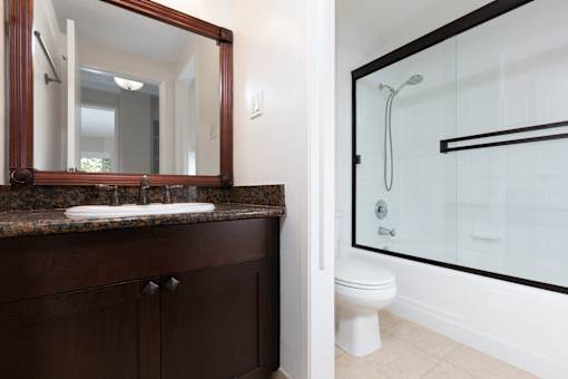 A bathroom with a sink, mirror, toilet and shower.