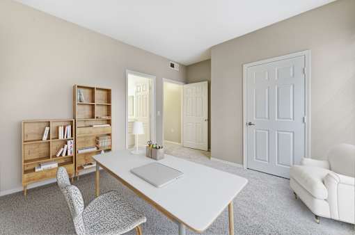 A room with a desk, chairs, and a bookshelf.
