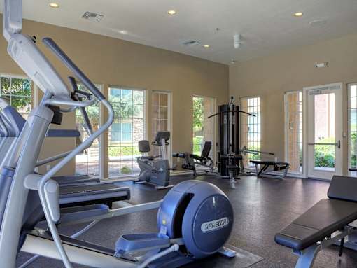 Three-Bedroom Apartments in Upland, CA - Park Central Apartments - Fitness Center with Cardio Equipment, Recessed Lighting, Large Windows, and a Glass Door.