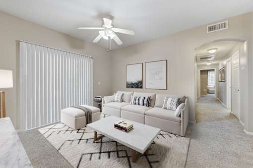 A living room with a white couch, a coffee table, and a ceiling fan.