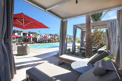 A patio with a red umbrella and a pool in the background.