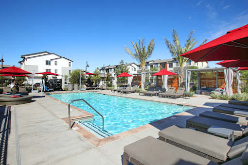 West Sacramento, CA Pet-Friendly Apartments - The Strand - Pool with Spa, Sundeck, Red Umbrellas, and Lounge Chairs.