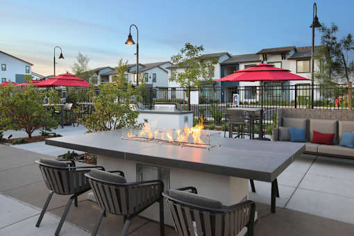 A patio with a fire pit and chairs.