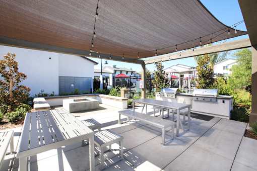 A patio with a table and chairs under a shade sail.